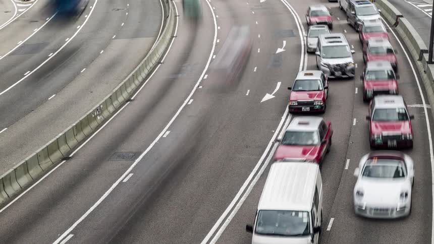 Cars travel in several different lanes in both directions on a city highway