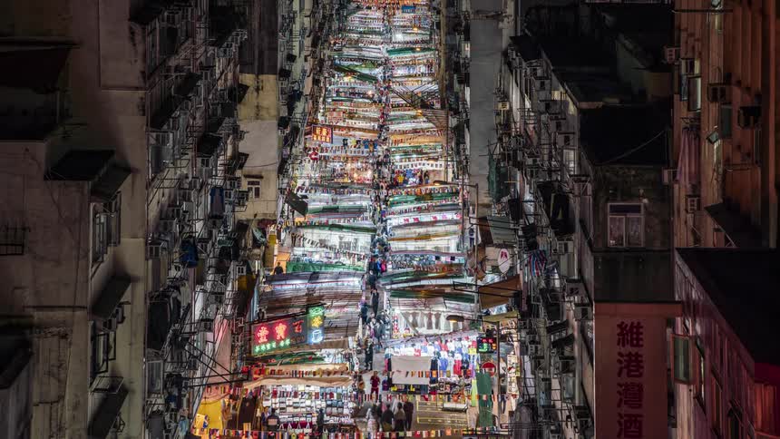 Aerial view of the city with tall buildings and people filling the market street at night