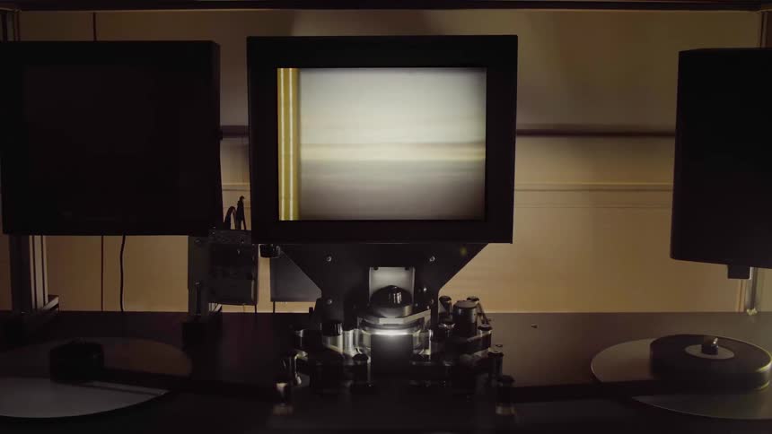 Film reels turn as landscape footage is shown on a monitor