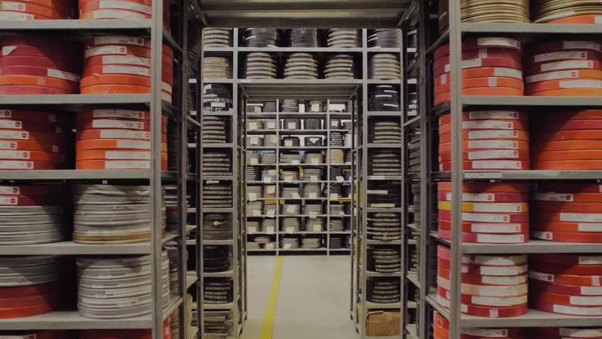 Labeled canisters of film stacked on shelves in a storage facility