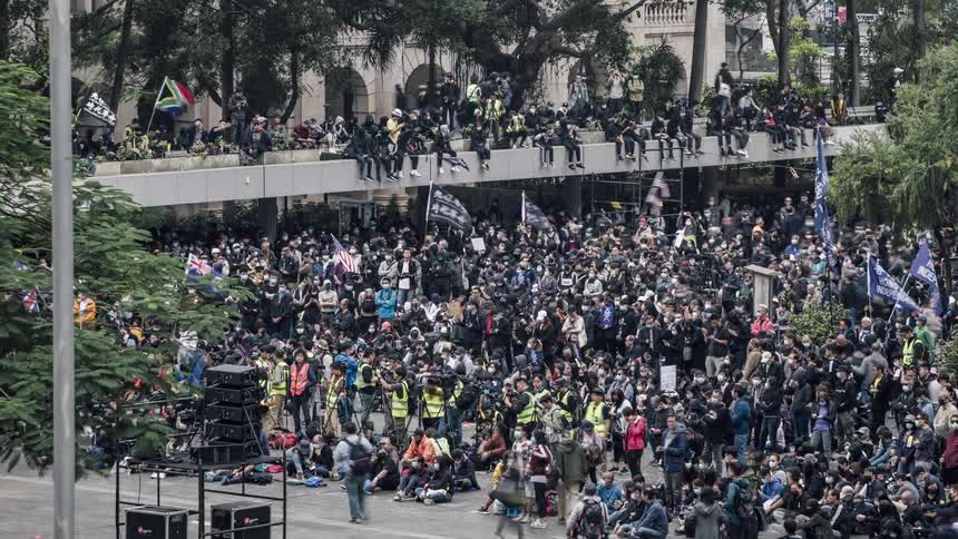 A crowd of people standing and sitting some with flags