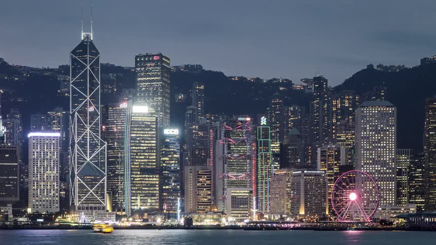 Time lapse of boats in the water and an amusement park in front of the city skyline