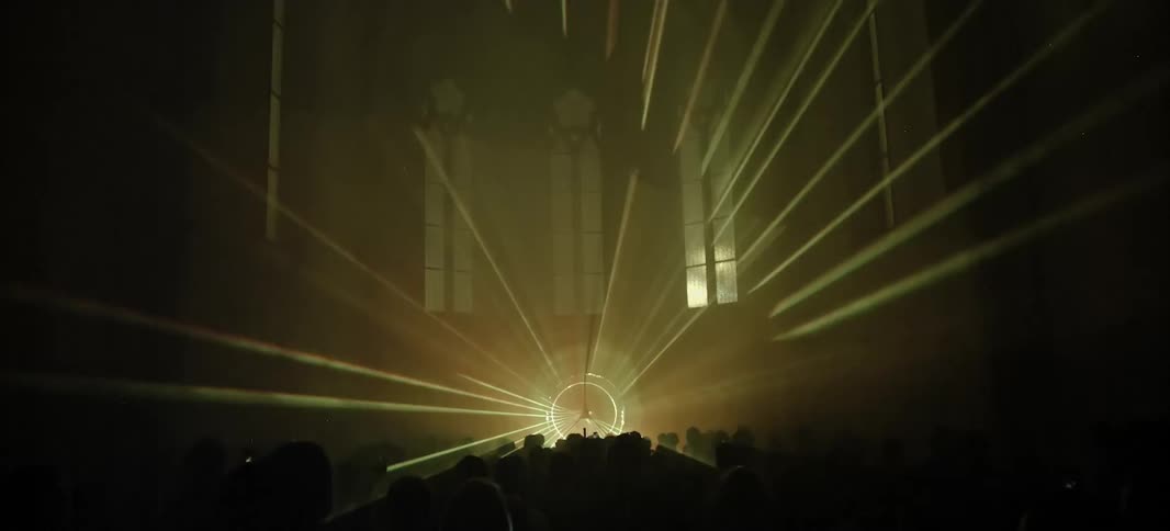 People standing in a large room with windows with a laser shining yellow light