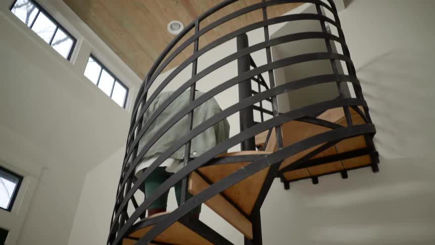 Person walking down a spiral staircase to the kitchen