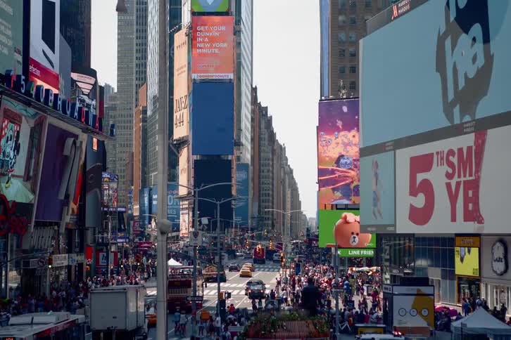 Crowds of people move through a busy downtown area