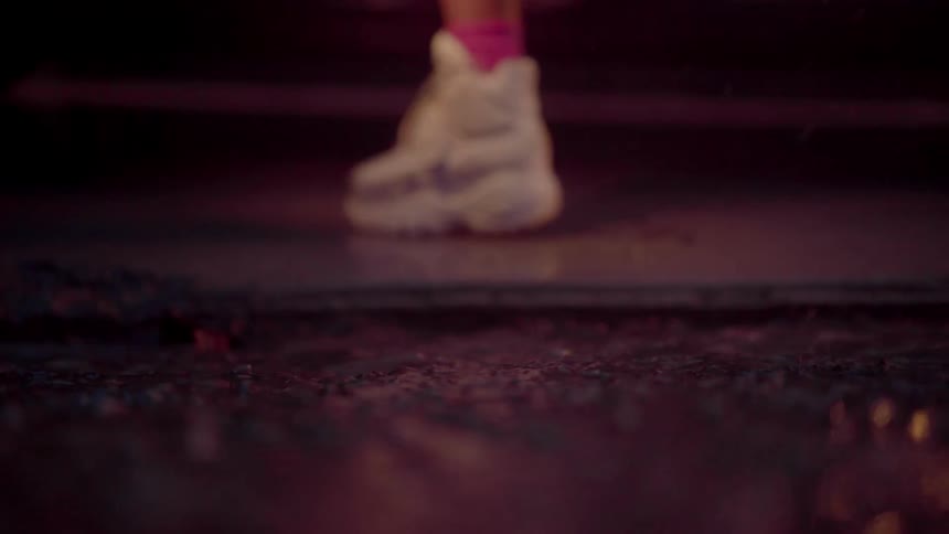 Rain falls heavily on the ground as a person wearing white sneakers with pink socks gets into a vehicle
