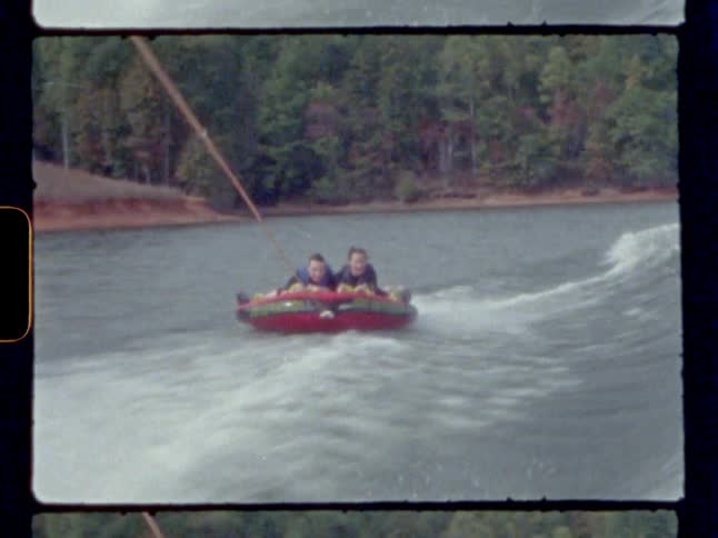 Two people on a raft being pulled by a boat by a rope