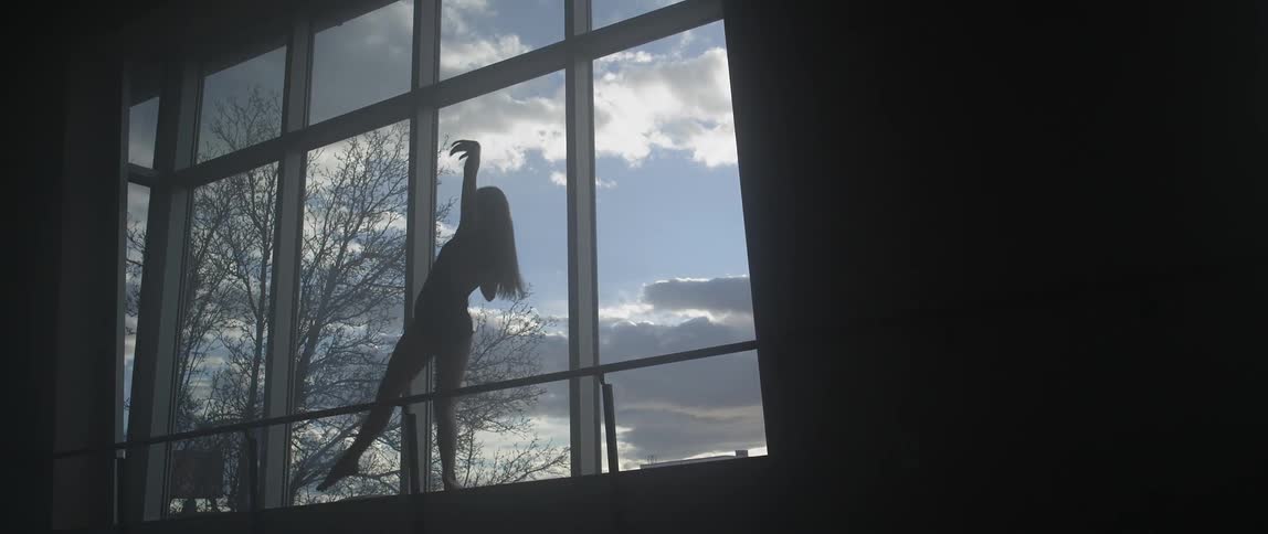 A woman dancing in front of windows