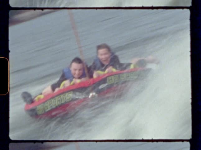 Two friends being pulled on a tube on the river