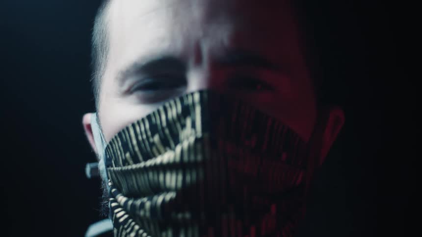 Man wearing a face mask looks at the camera on a black background
