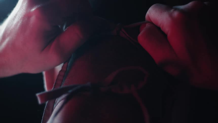 Man ties face mask in a dark lit room
