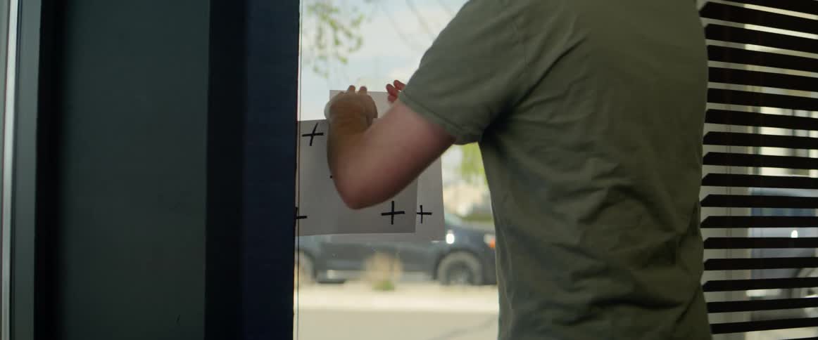 An employee of a store changes paper signs on a window