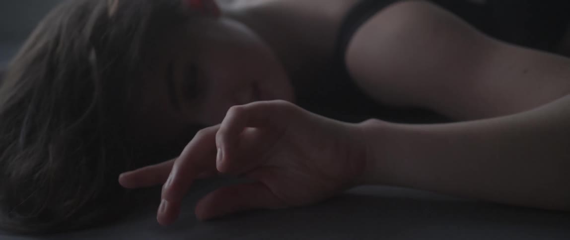 A woman in black drags her arm across the floor and smiles
