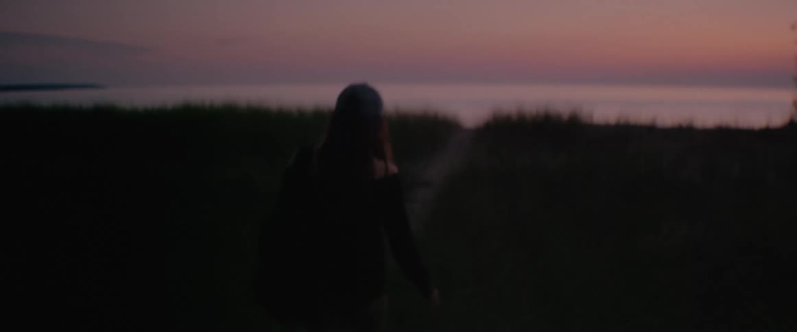 Woman walks on a trail near the fields at dusk