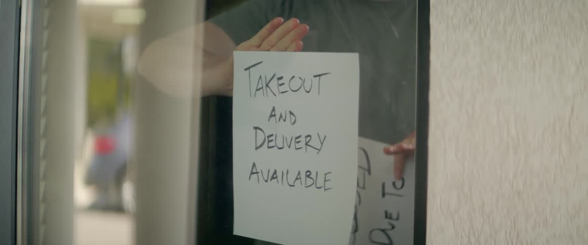 A man takes down a closed due to coronavirus sign and puts up one that states takeout and delivery available