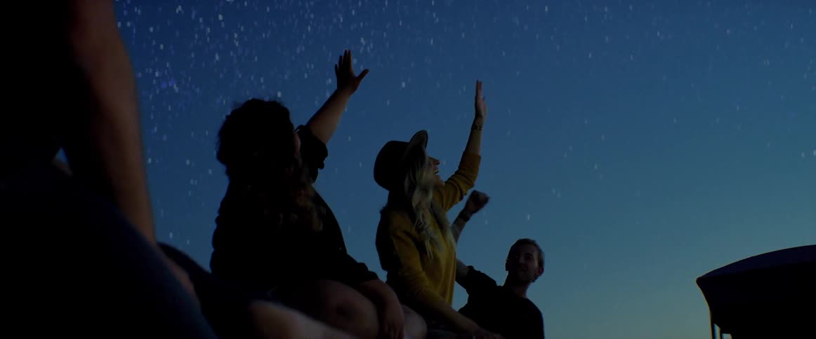 Four people talking and pointing at the night sky