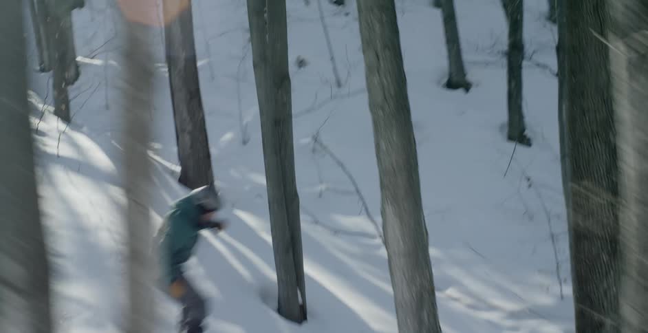 A skier skiing at high speed down a slope through a wooded area