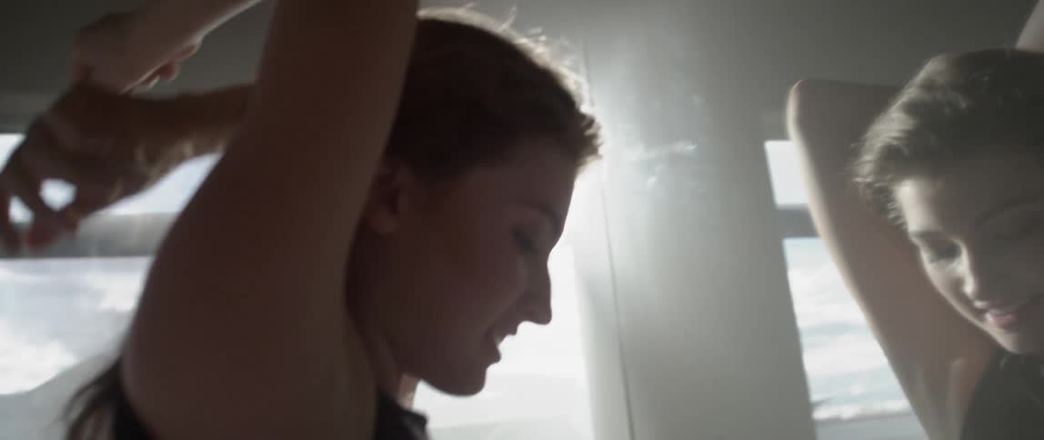 A woman in black dances in front of a window