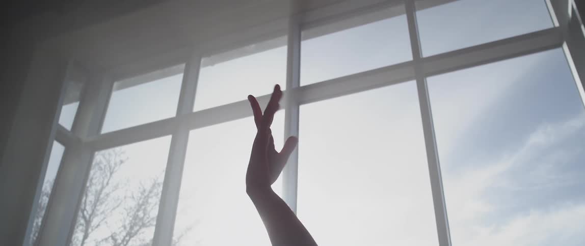 A person is waving their hands around in front of a window