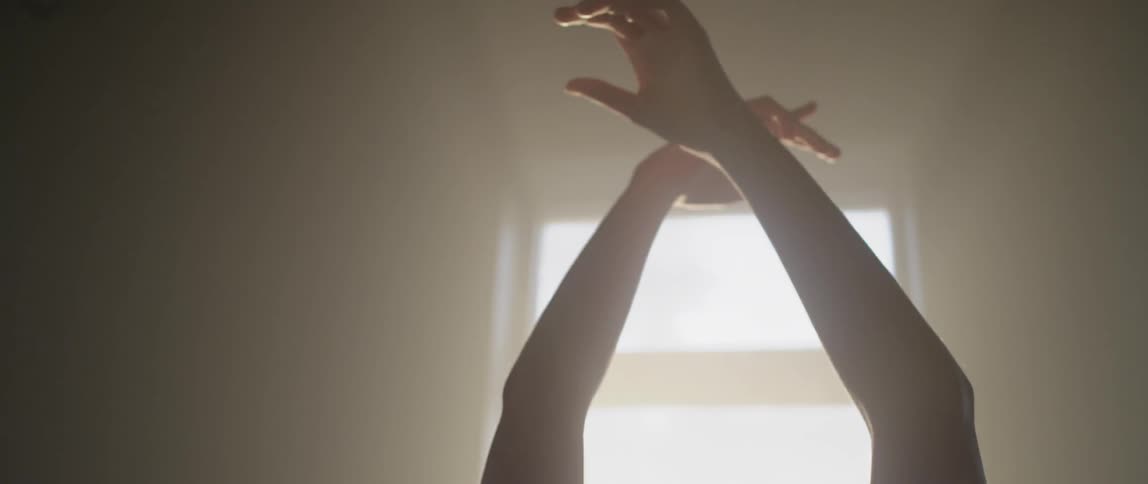 A woman stretches in front of a sunny window