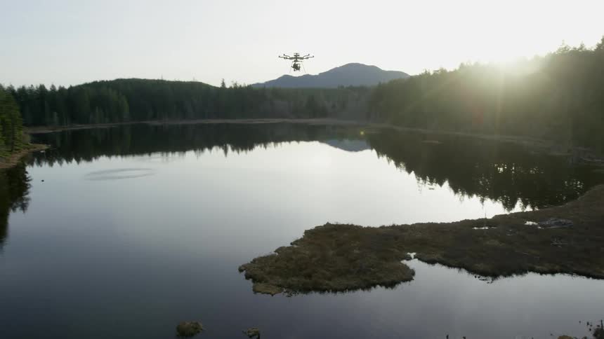A drone hovers over a calm mountain lake