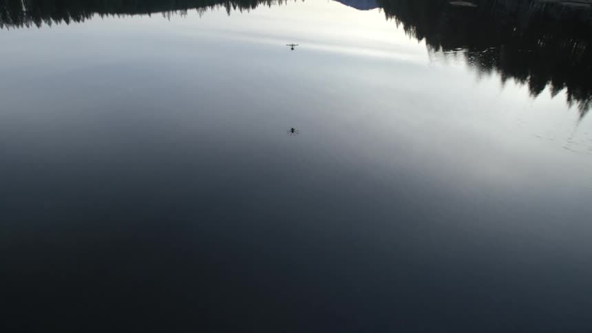 A drone flies over a slick lake in the evening