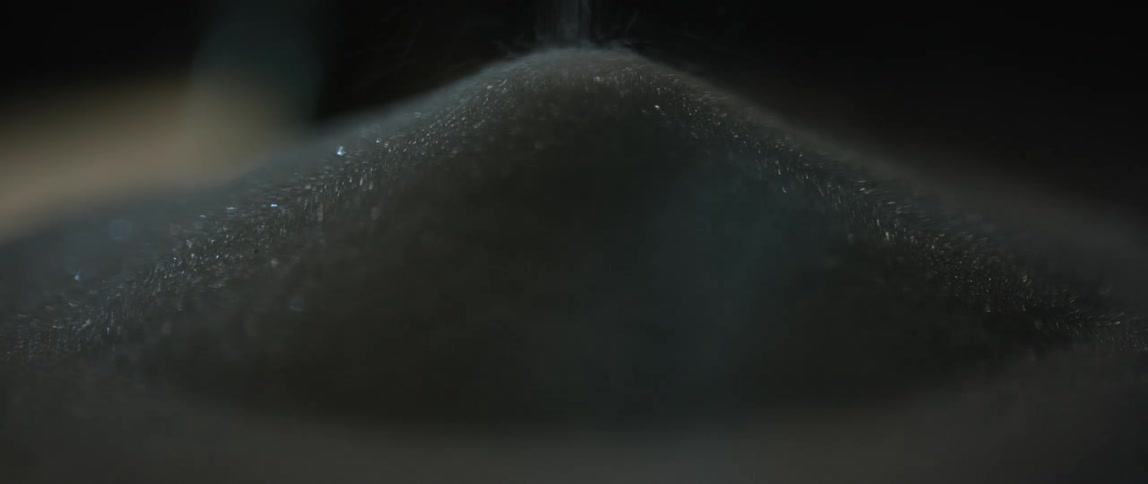Black sand falling into a pile