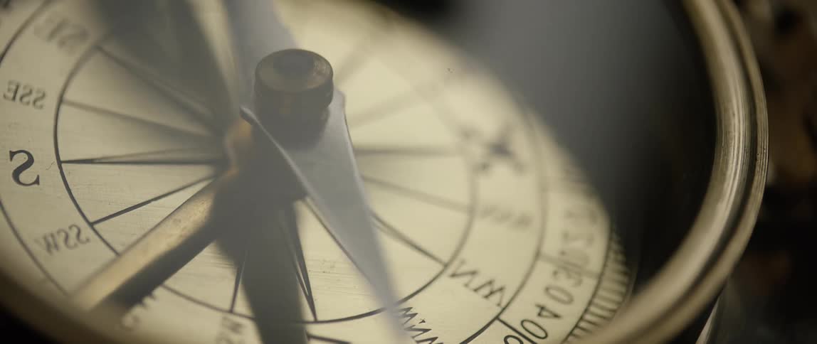 The needle of a brass compass swinging back and forth