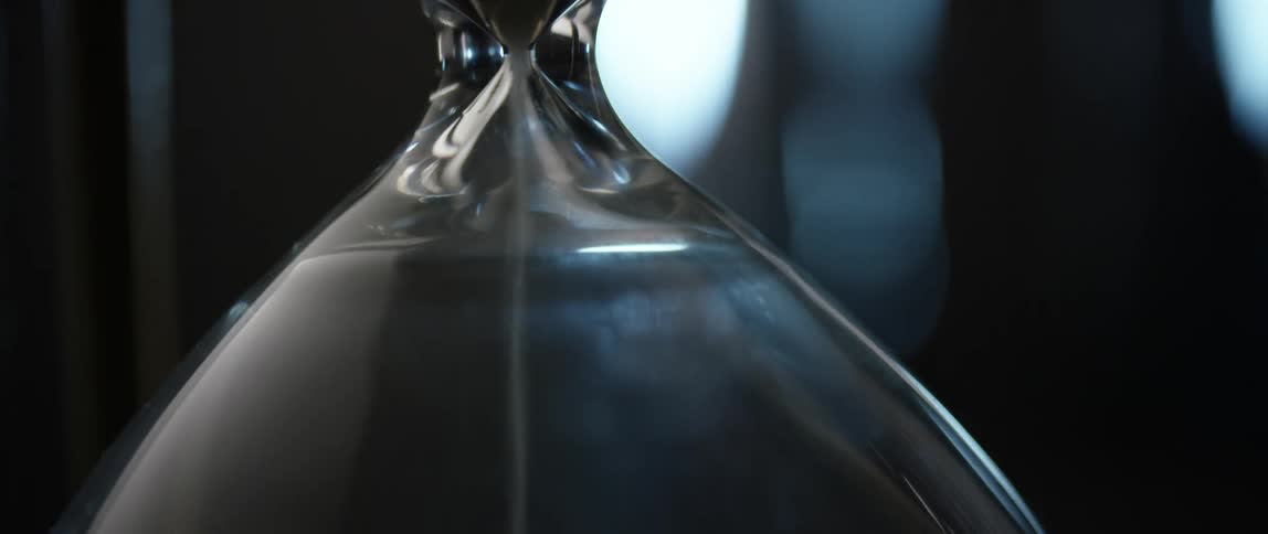 Sand falling in a hourglass on an indoor table