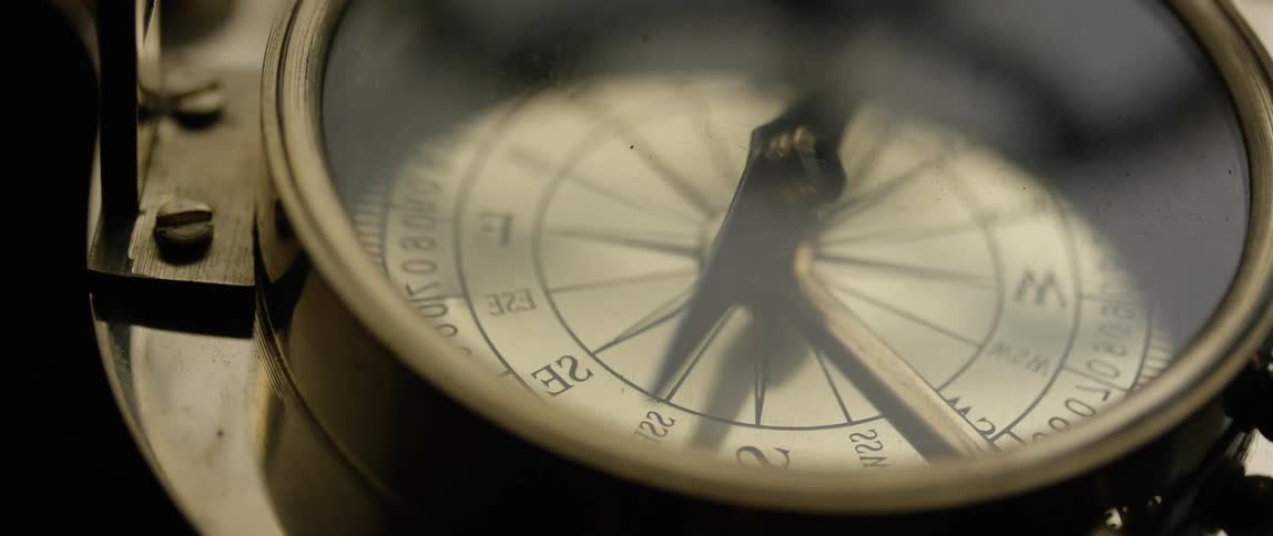 The needle of a compass turns as light and shadow play across its face