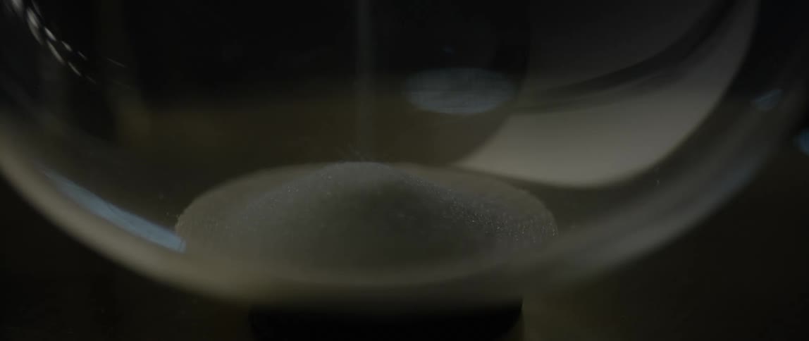 Sand falling to bottom of glass jar in a mound