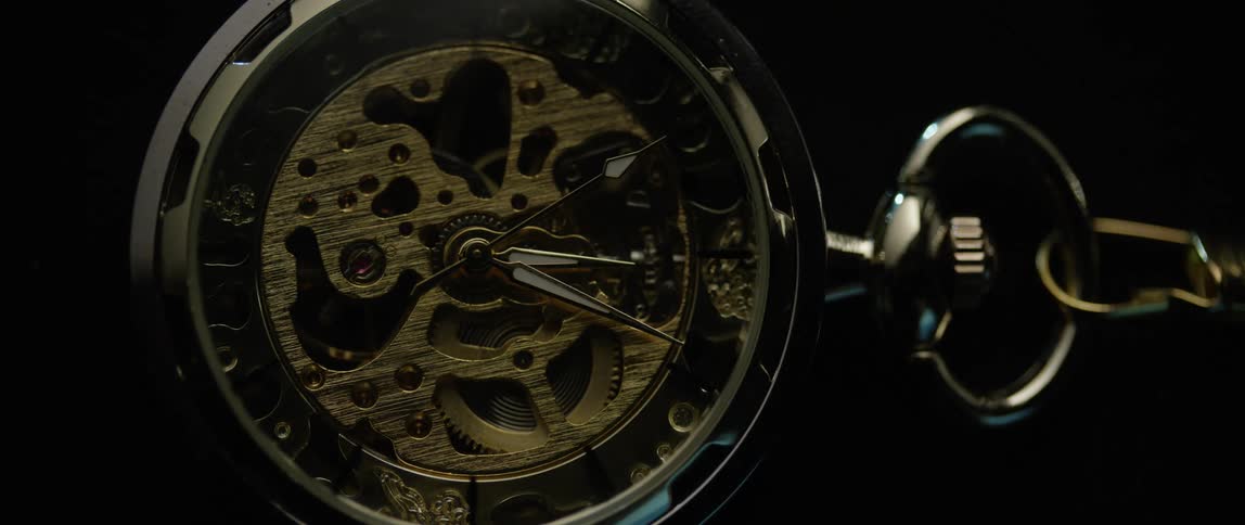 The second hand ticks on a pocket watch with exposed gears