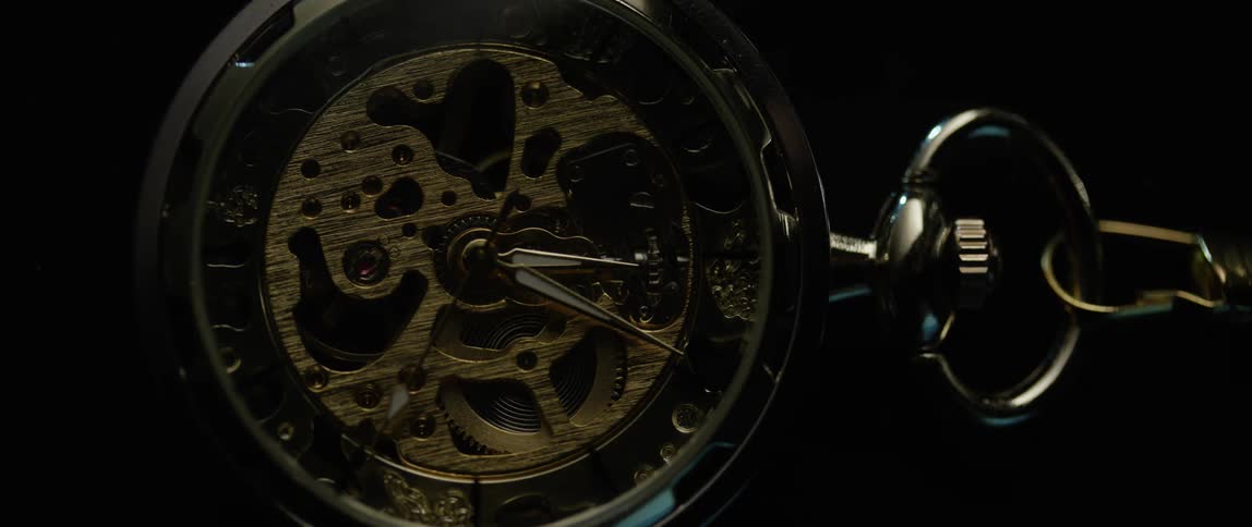 The seconds hand of a pocket watch ticks across the face as the works and gears are visible