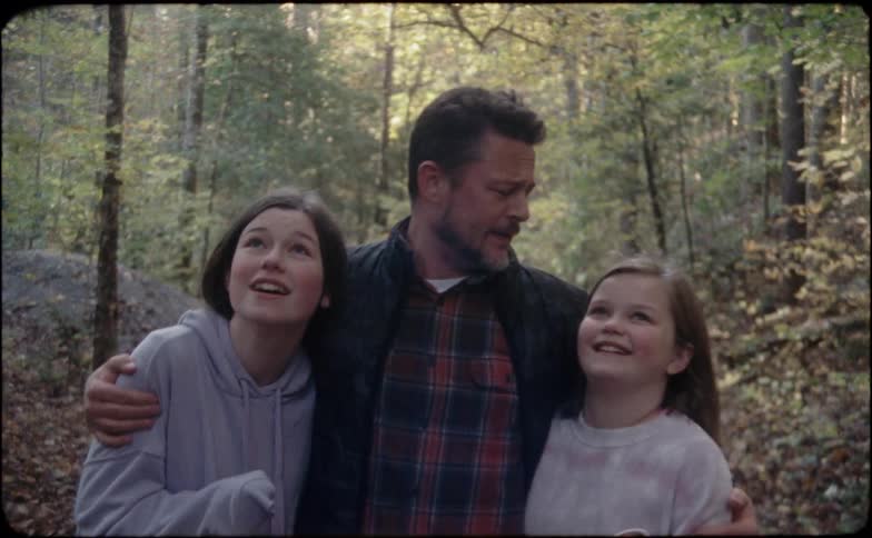 A father with his two daughters walking and hugging in the woods