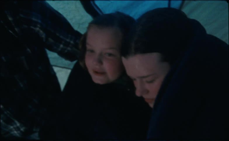 Man taking care of his daughters inside a camping tent amidst a rain storm