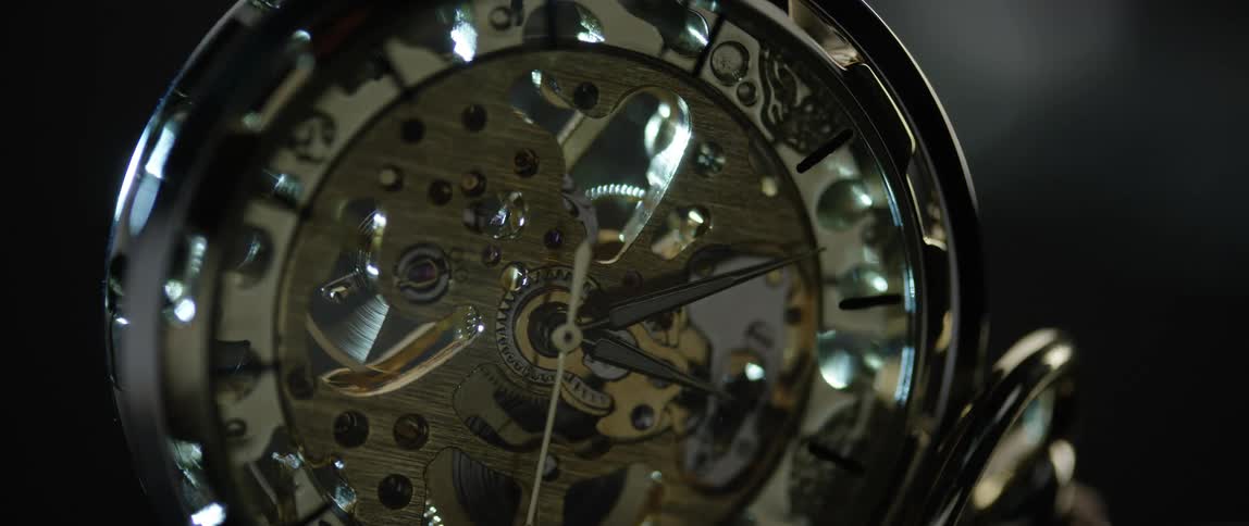 Light reflects off the face of an exposed gear pocket watch