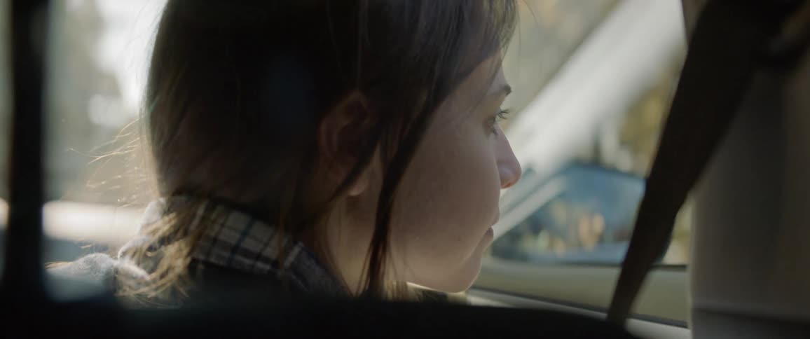 Girl looks out the window of a moving car