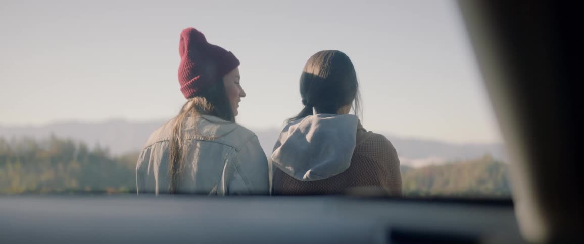 Two white women talking and relaxing while sitting and watching the landscape