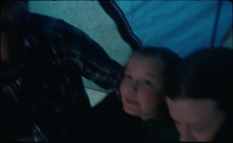 A man and his children sit in a tent while it rains