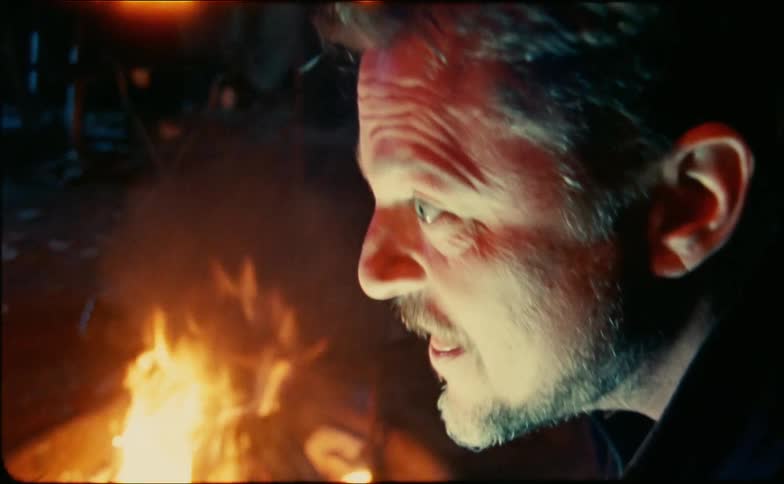 A man tells an animated story over a campfire