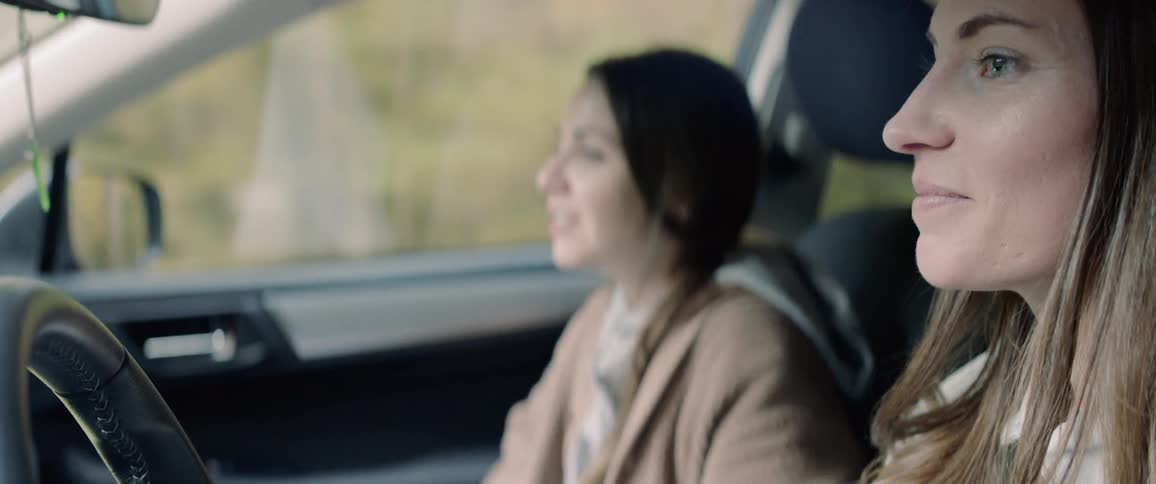 A pair of women laughing and chatting while traveling in a car