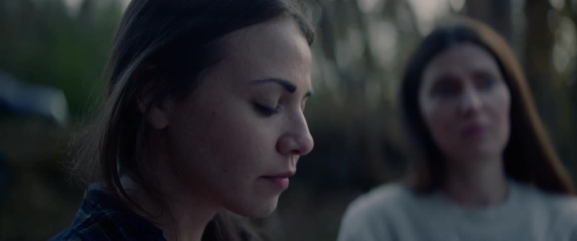 Two women stand by a field looking forward