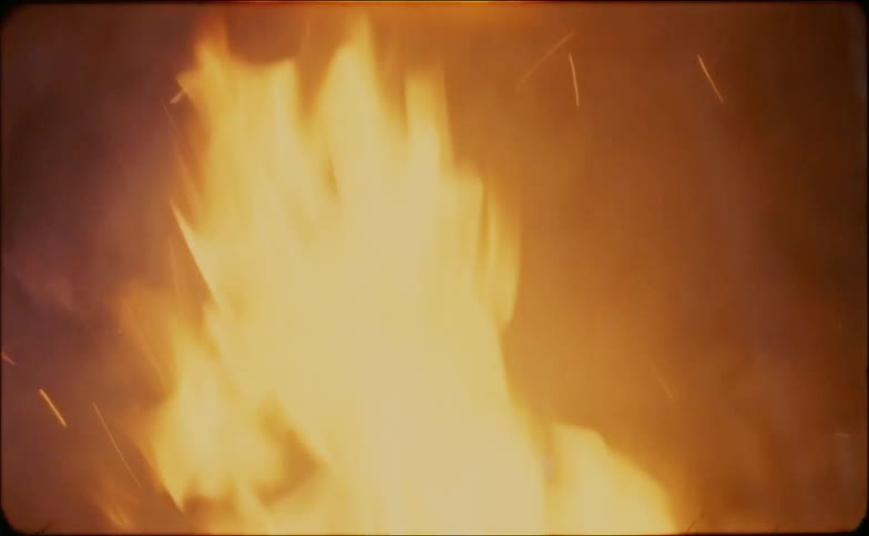 Smoke and embers rise up from flames at night