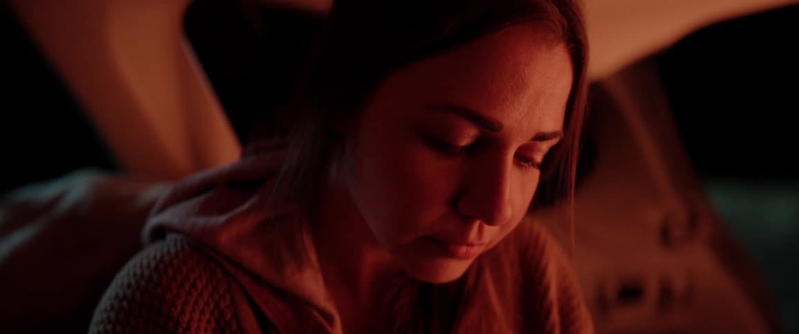 Woman sitting near the campfire reads the notebook at night