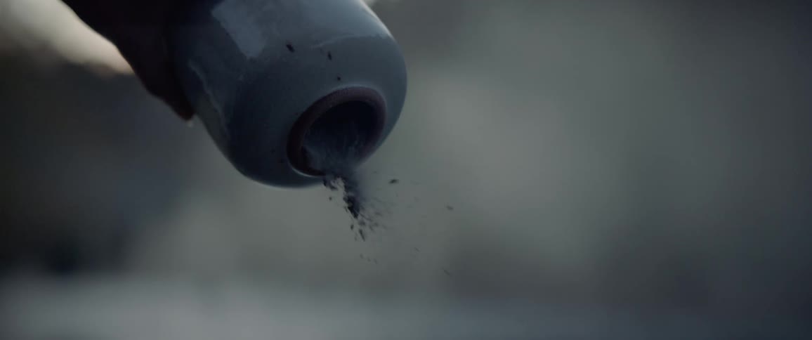 Ashes of a loved one being poured out of urn outdoors in nature