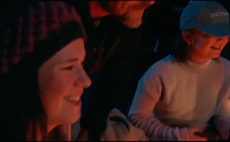 Father talking and having fun with his daughters next to a camp fire on the woods