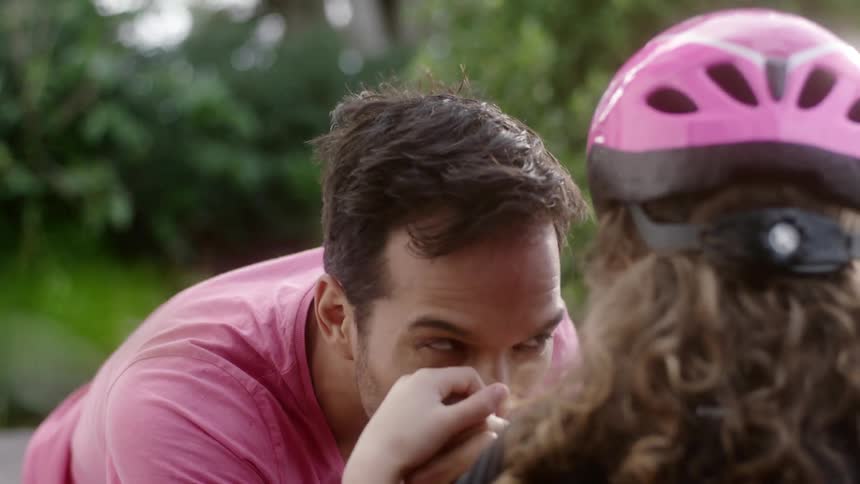 A man hugs a young girl wearing a bike helmet