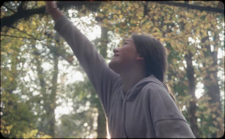 A young girl reaches her arm up and laughs