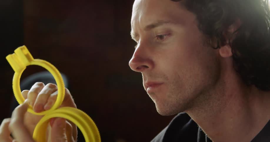 A man examining and fiddling with plastic yellow gears