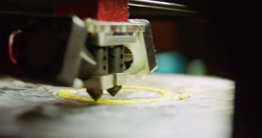 A 3d printer printing a yellow cylinder